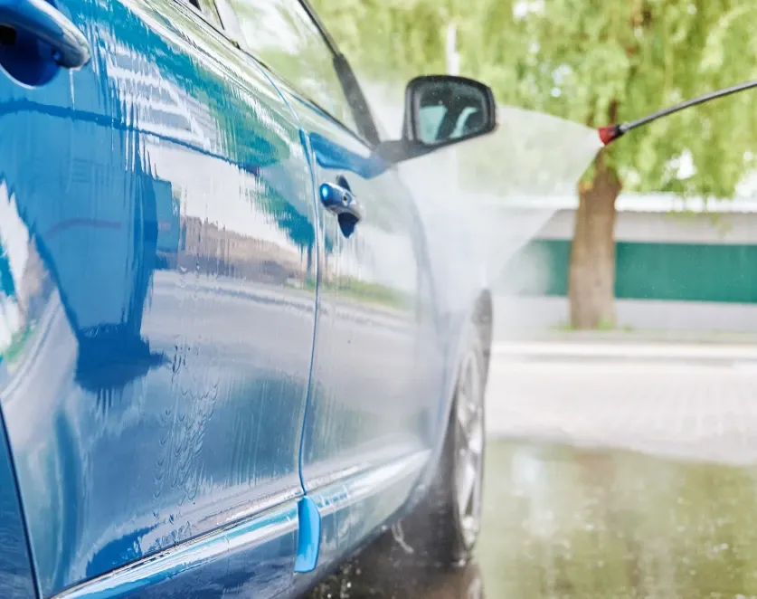 Customer rinsing a vehicle in a D&S IQ Self Wash bay
